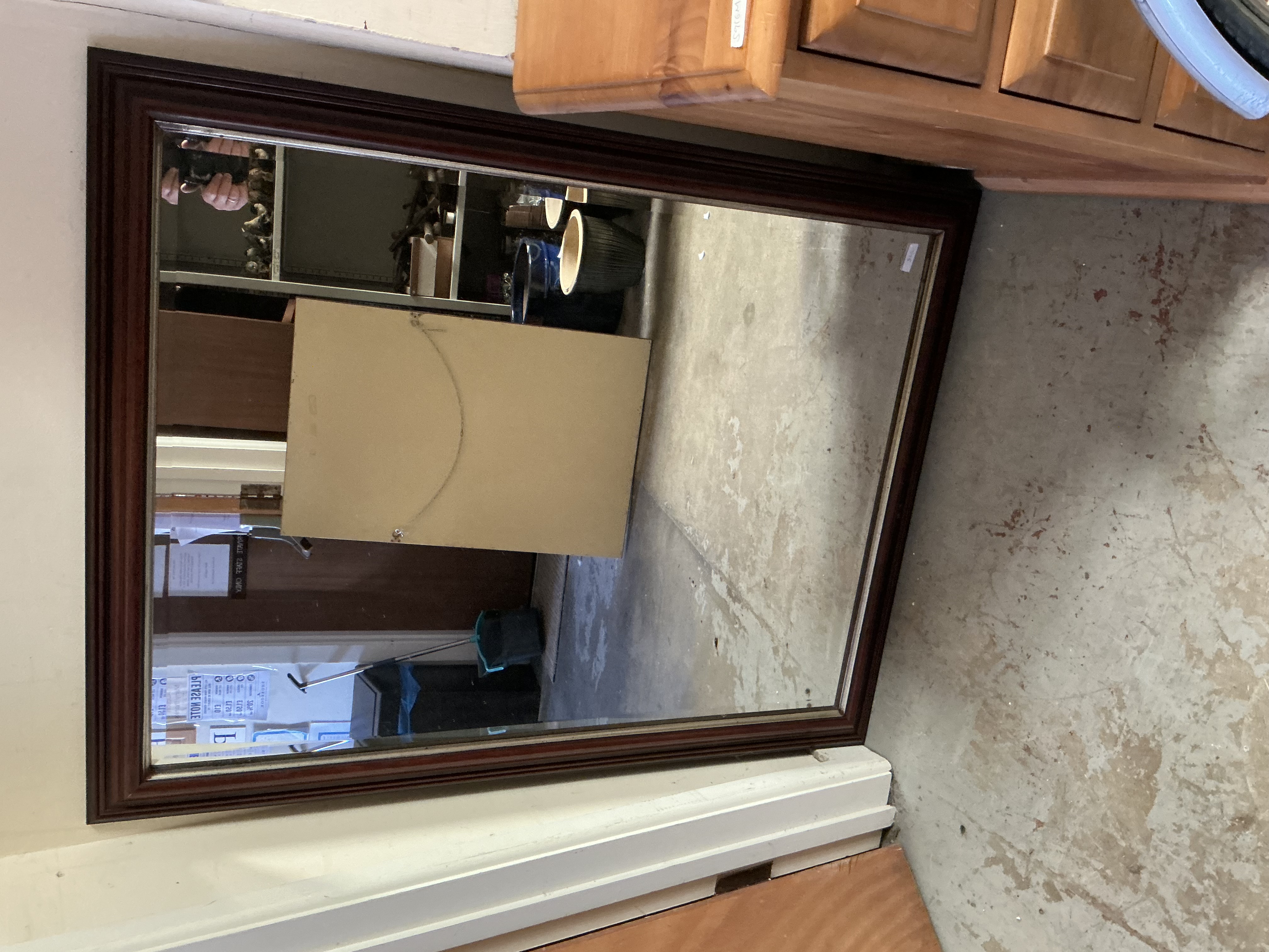 A large mahogany-finished rectangular wall mirror with a bevelled plate
