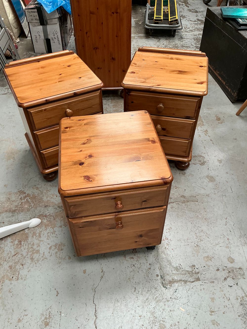 Lot 466: A suite of Ducal pine furniture comprising a pair of three-drawer bedside cabinets and one filing cabinet