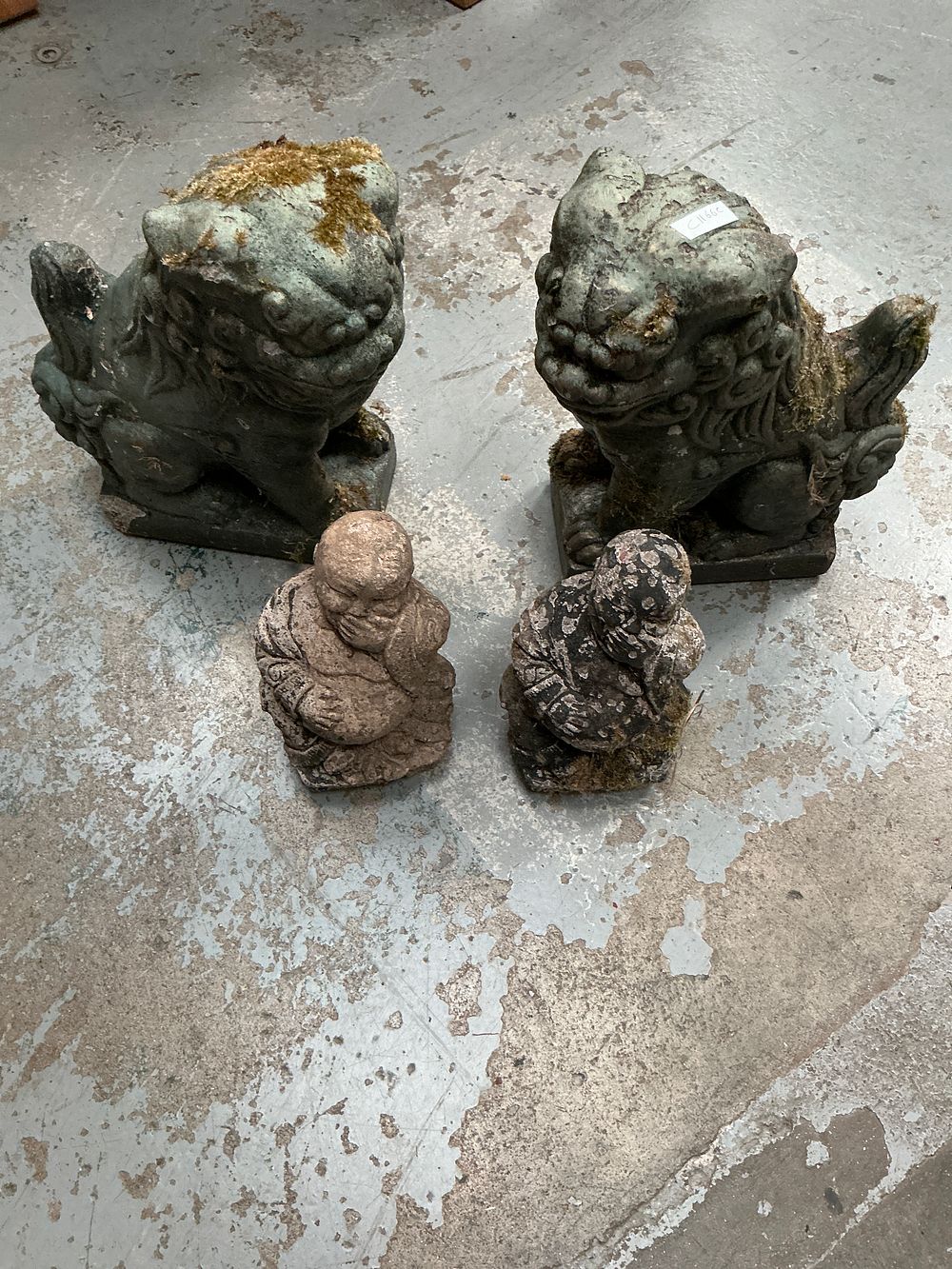 Lot 86: Collection of four weathered cast stone Oriental style garden ornaments comprising a pair of guardian lions and two Budai figures