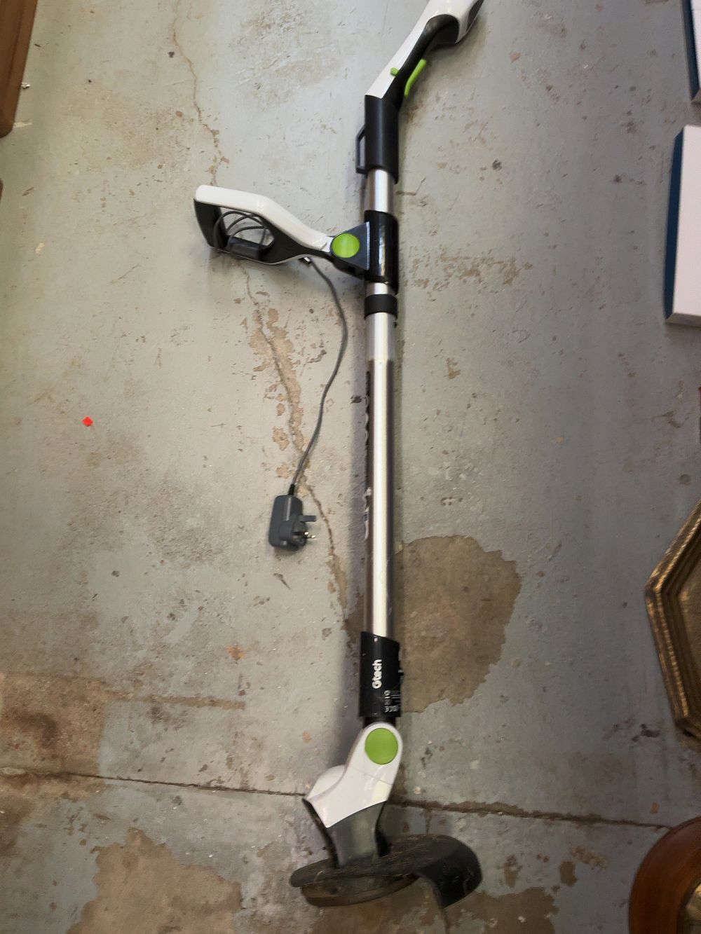 Lot 219: A Gtech Plastic and Metal Cordless Grass Trimmer with Charging Adapter