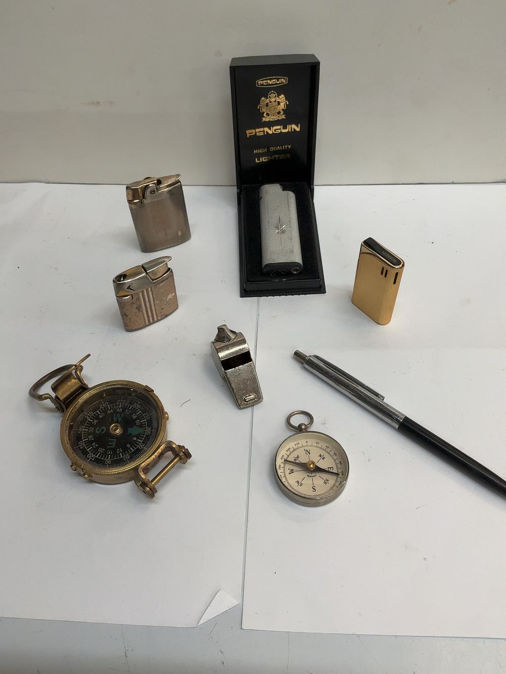 Lot 442: An Assortment of Vintage Personal Accessories and Navigational Tools Including Ronson lighters and Penguin Examples with Presentation Case
