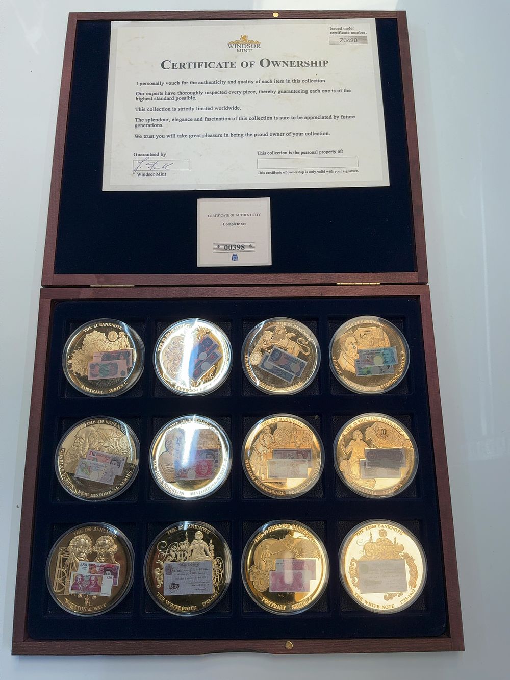 Lot 82: A Set of Twelve 2017 Windsor Mint Gold-Plated Copper British Banknote Commemorative Medallions with Presentation Case