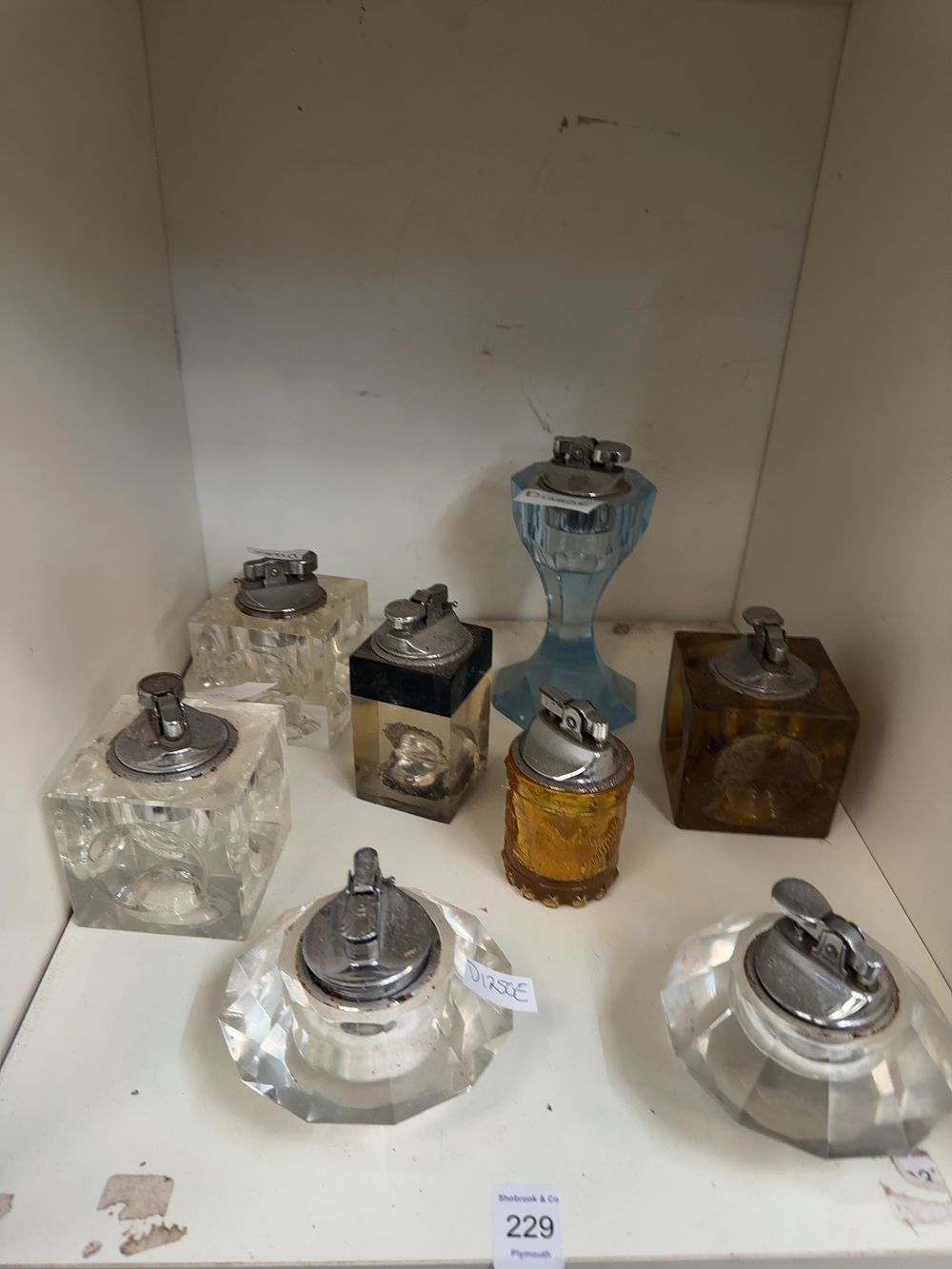 Lot 229: A Collection of Vintage Glass and Resin Table Lighters including an Amber Glass Eagle Motif Example
