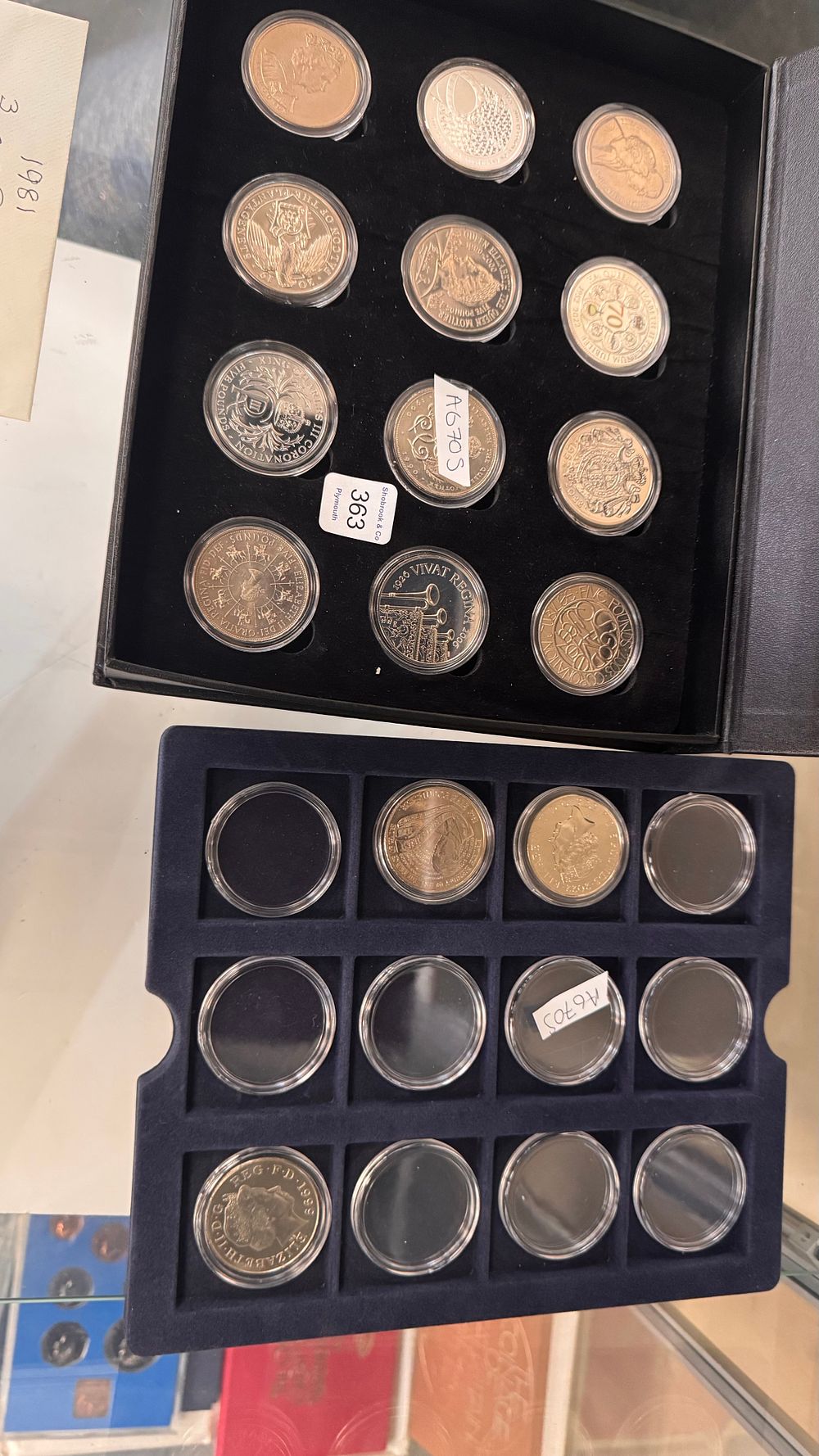 Lot 363: A Collection of Fifteen United Kingdom Commemorative Five Pound Coins and Empty Capsules in Two Trays