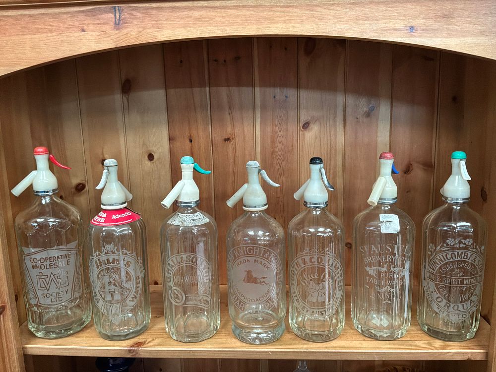 Lot 205: A Collection of Seven Vintage Etched Glass Soda Siphons Including St Austell Brewery Examples