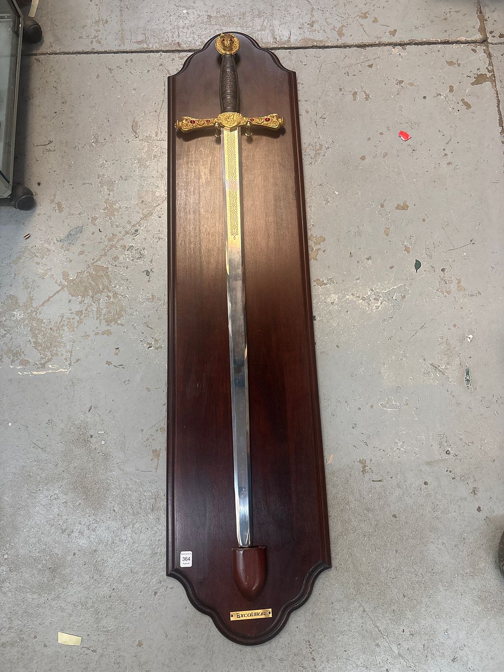 Lot 365: A Decorative Excalibur Motif Wall Mounted Display Sword on Contoured Wooden Plaque