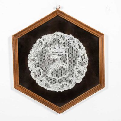 תמונת תחרה . רקמת תחרה בלגית בעבודת יד, 
כנראה סמל משפחה, 
ממוסגרת במסגרת עץ משושה. 
מידות 24/28 ס"מ