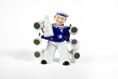 בקבוק פיגורטיבי בצורת מלח שיכור. נושא בקבוק בידו ומשמש מתלה ל-6 כוסיות קטנות 
חתום בבסיס 
20/176 ס"מ