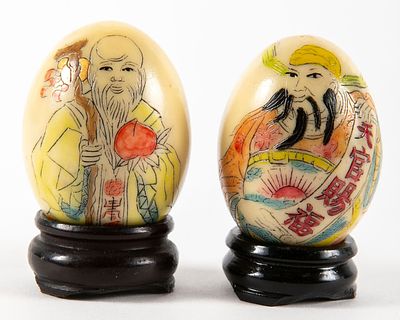 שתי ביצי אבן חרוטות ומצויירות ביד, בדמויות של אלים סיניים. גובה 6 ס"מ