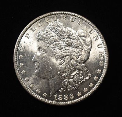 1886 MORGAN DOLLAR AU/BU. CHECK OUT OUR UPCOMING AUCTIONS ESTIMATE $75 - $100.
