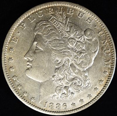 1886-O MORGAN DOLLAR AU. CHECK OUT OUR UPCOMING AUCTIONS ESTIMATE $150 - $200.