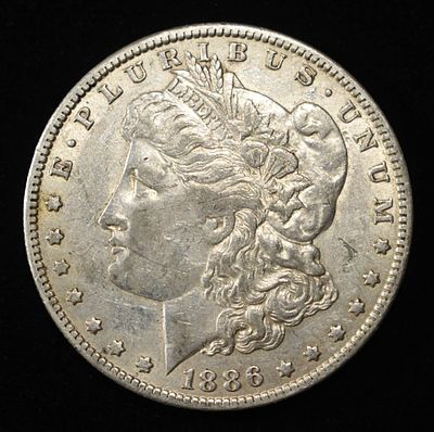 1886-O MORGAN DOLLAR AU. CHECK OUT OUR UPCOMING AUCTIONS ESTIMATE $130 - $150.