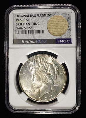1927-S PEACE DOLLAR NGC BU WITH BAG FRAGMENT. NICE CH BU COIN. ESTIMATE $300 - $400.