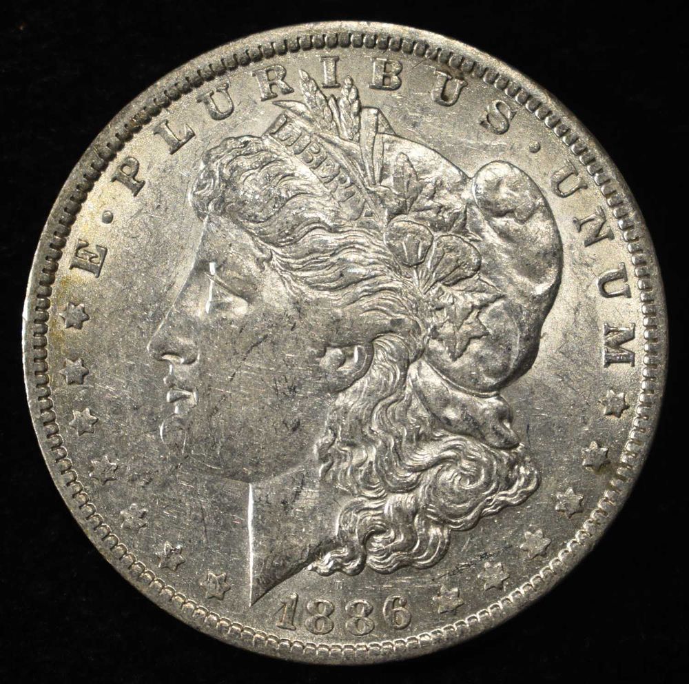 1886-O MORGAN DOLLAR AU. CHECK OUT OUR UPCOMING AUCTIONS ESTIMATE $170 - $200.