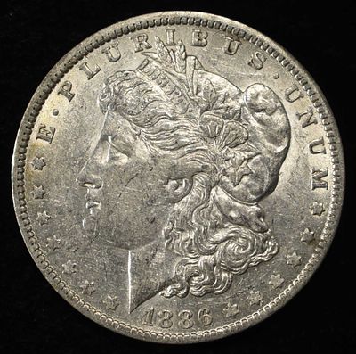 1886-O MORGAN DOLLAR AU. CHECK OUT OUR UPCOMING AUCTIONS ESTIMATE $170 - $200.