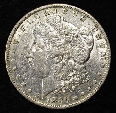 1886-O MORGAN DOLLAR AU. CHECK OUT OUR UPCOMING AUCTIONS ESTIMATE $170 - $200.