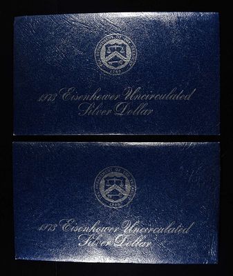 (2) 1973 EISENHOWER DOLLAR BLUE PACKAGING. BID WITH SILVER CITY AUCTIONS ESTIMATE $75 - $100.