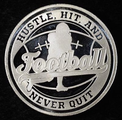 FOOTBALL 1 OZ .999 SILVER ROUND. BID WITH SILVER CITY AUCTIONS ESTIMATE $120 - $160.