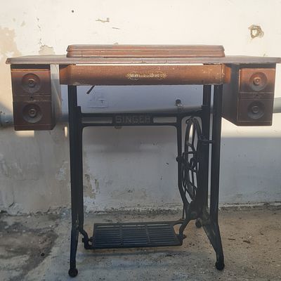 רגלי מכונת תפירה זינגר , גלגל מסתובב ע"י דוושת רגל, עליו שולחן עץ עם 4 מגירות ( ככל הנראה 