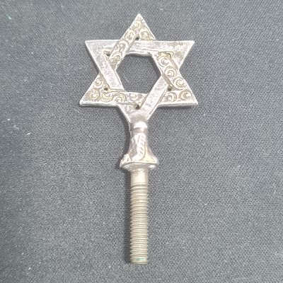 מגן דוד מכסף (יתכן שהבורג לא כסף), חלק מרימון של ספר תורה 
משקל כ 9.6 גרם 
אורך כולל כ 6 ס"מ