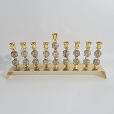 חנוכיה מיוחדת ומרשימה, עשויה כולה מתכת מצופה זהב 24 קראט, גובה כ 13 ס"מ, רוחב כ 26 ס"מ.