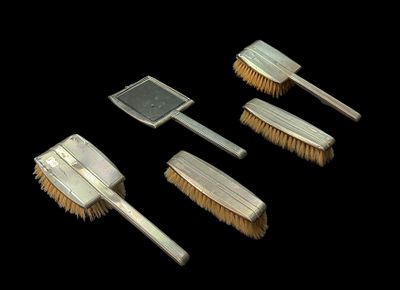 Conjunto de “toilette”, composto por 4 escovas e 1 espelho, com cabos e capas de prata inglesa 