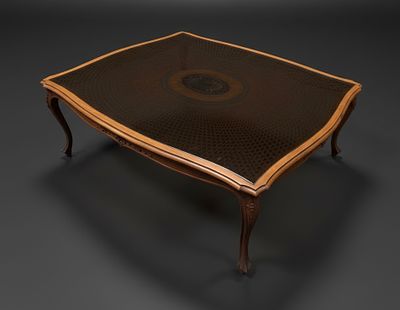 Mesa baixa, de mogno com trabalho de talha, com tampo de palhinha com vidro. Alt. 0,45. Med. 1 