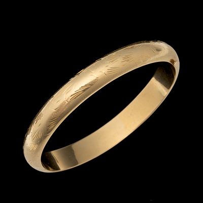 A BRITE-CUT 14K GOLD LADIES BANGLE BRACELET. The hinged bangle is decorated in hand engraved 
