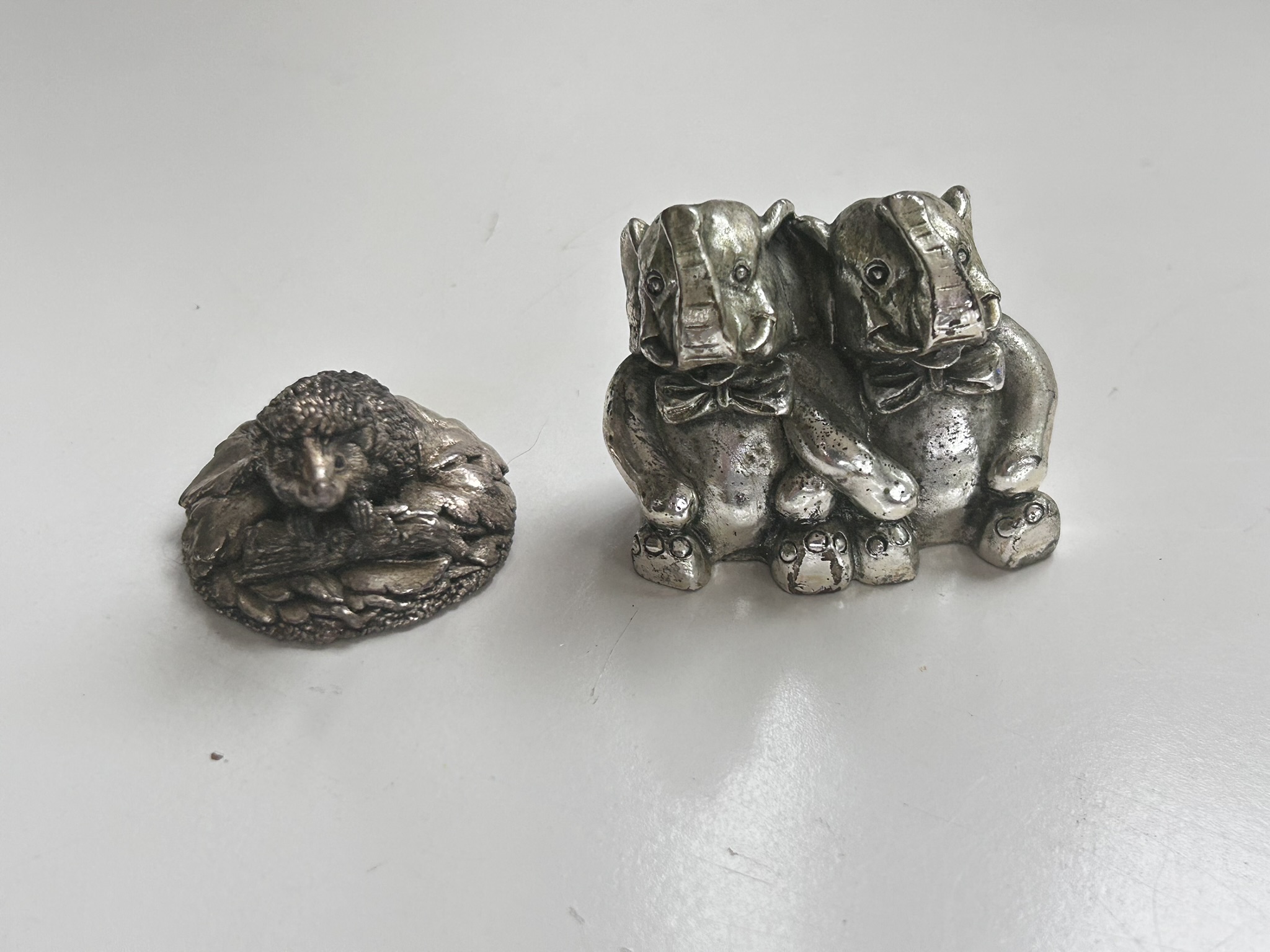 A filled silver ornament in the form of a hedgehog, with full hallmarks and a pair of silver coloured metal elephants Argento Italy