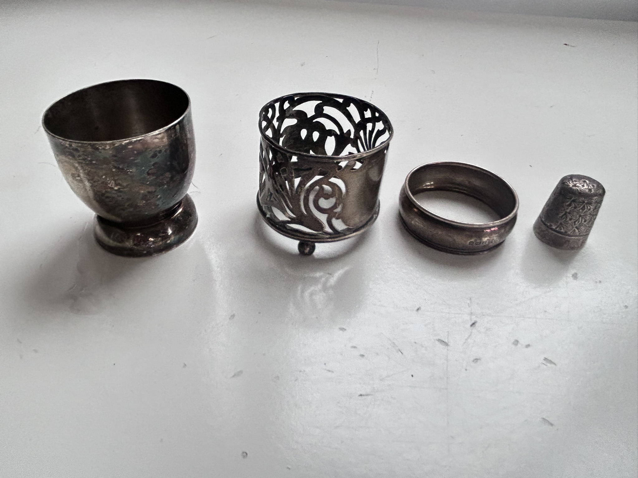 A silver napkin ring, silver thimble and silver candle holder (missing glass insert), all hallmarked and an antique silver coloured metal egg cup (no marks), total weight 72g