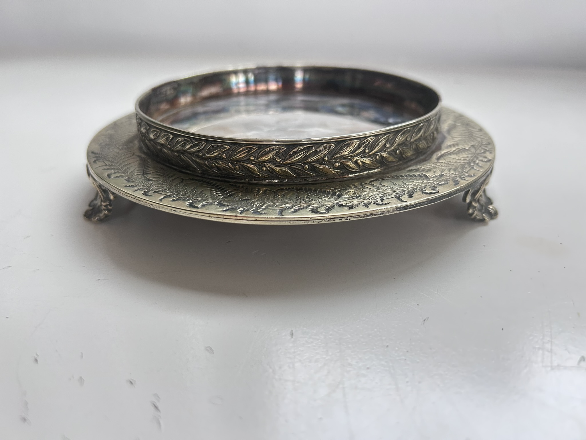 A white metal footed wine coaster stand or bottle stand salver with markings to the underside