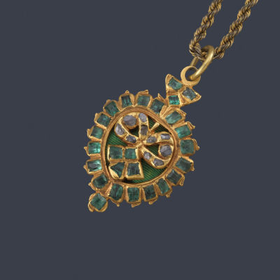: Colgante con centro en forma de lazada con esmeraldas calibradas y diamantes talla roca, en 