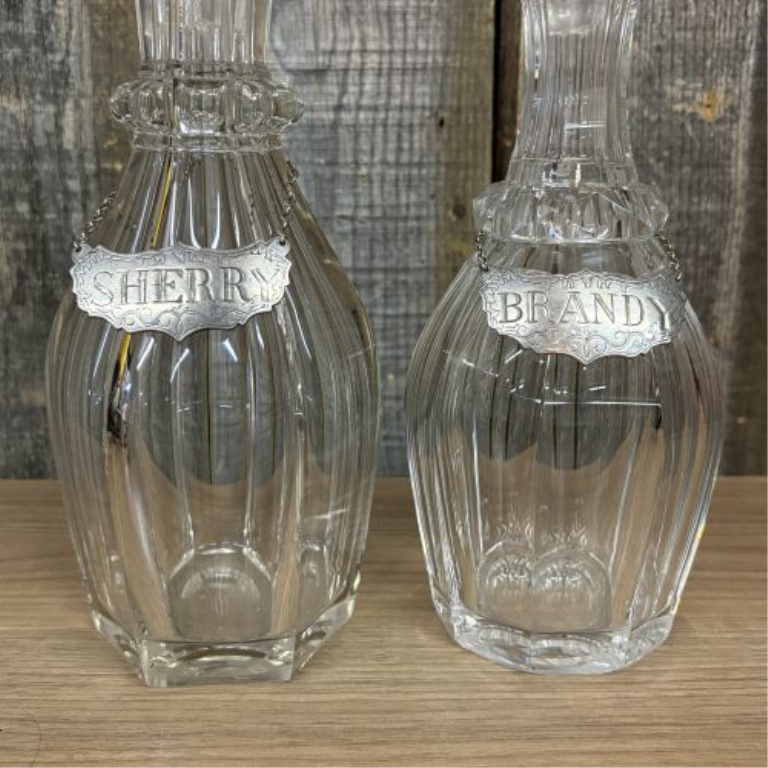 A Pair of Cut Glass Liquor Decanters with Metal Labels and Spire Stoppers
