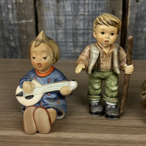 A Set of Four Goebel M.I. Hummel Hand-Painted Ceramic Musical and Wandering Child Figurines