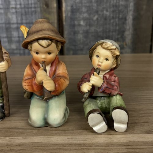 A Set of Four Goebel M.I. Hummel Hand-Painted Ceramic Musical and Wandering Child Figurines