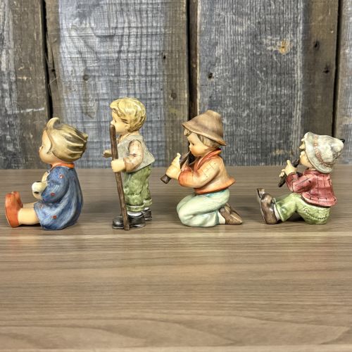 A Set of Four Goebel M.I. Hummel Hand-Painted Ceramic Musical and Wandering Child Figurines