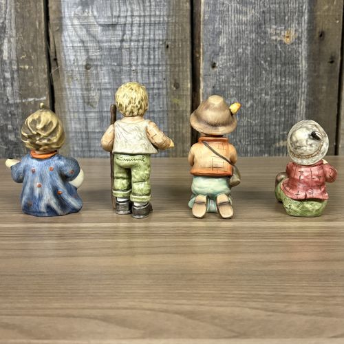 A Set of Four Goebel M.I. Hummel Hand-Painted Ceramic Musical and Wandering Child Figurines