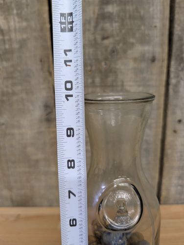 A Collection of Vintage Glass and Clay Marbles in an Embossed Paul Masson Carafe