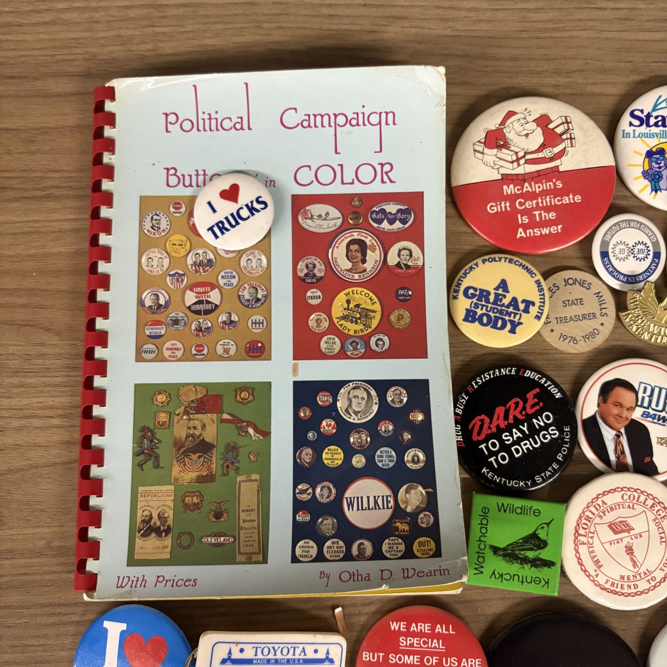 An Assortment of Vintage Pinback Buttons, Keychains, and Political Button Reference Book