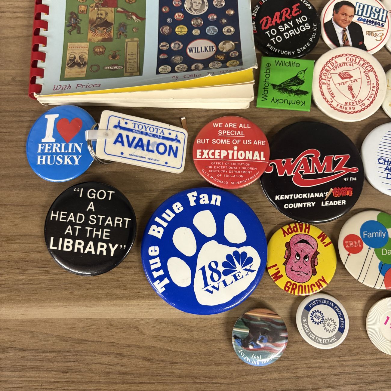 An Assortment of Vintage Pinback Buttons, Keychains, and Political Button Reference Book