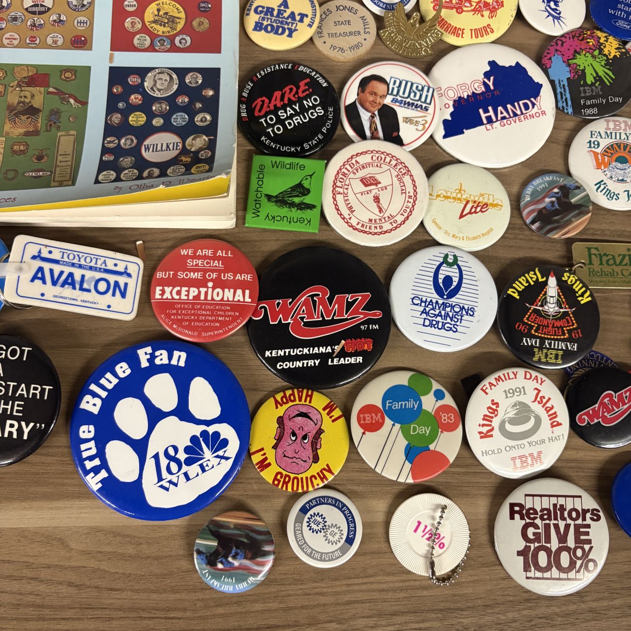 An Assortment of Vintage Pinback Buttons, Keychains, and Political Button Reference Book