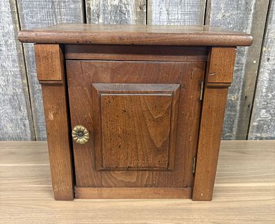 Small Single Door Stained Wood Cabinet with Raised Panel. A small, rectangular wooden cabinet or 