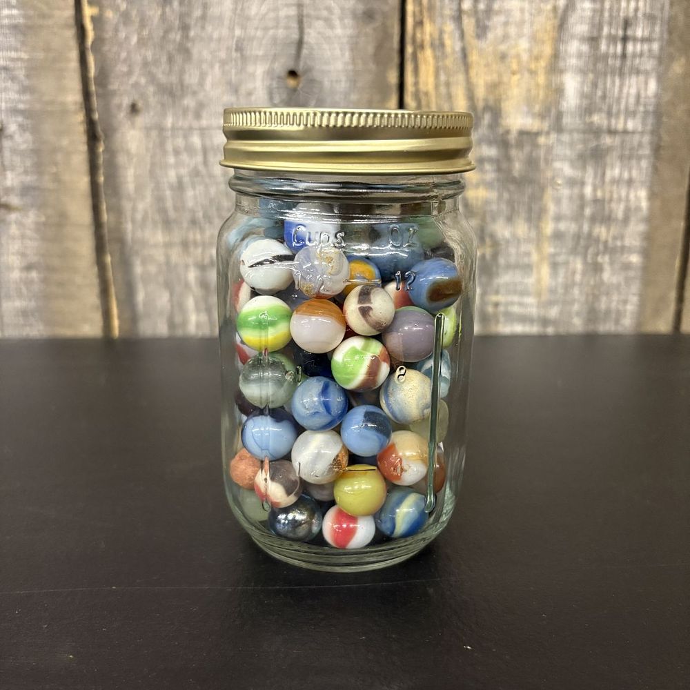 Lot 306: A Collection of Assorted Vintage and Contemporary Glass Marbles in a Graduated Glass Jar