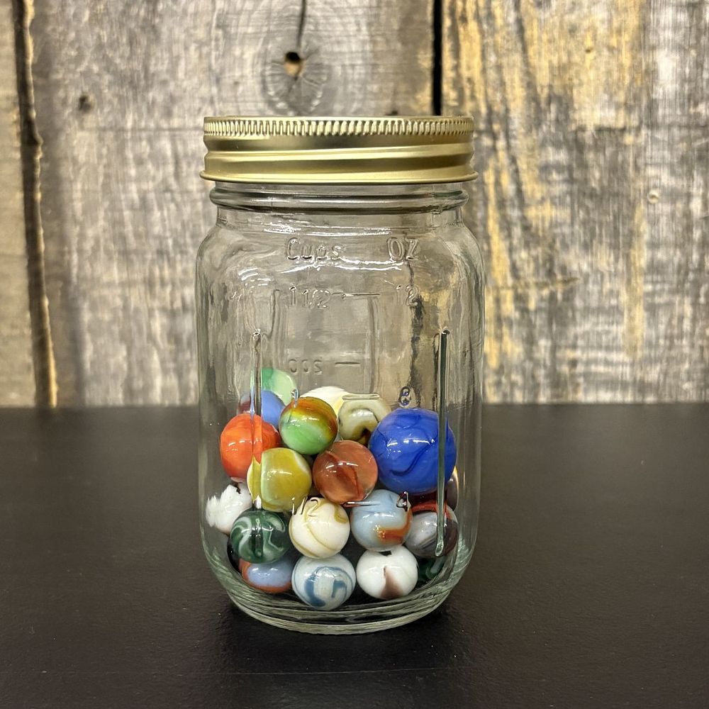 Lot 307: An Assortment of Vintage Glass Marbles in a Graduated Glass Storage Jar
