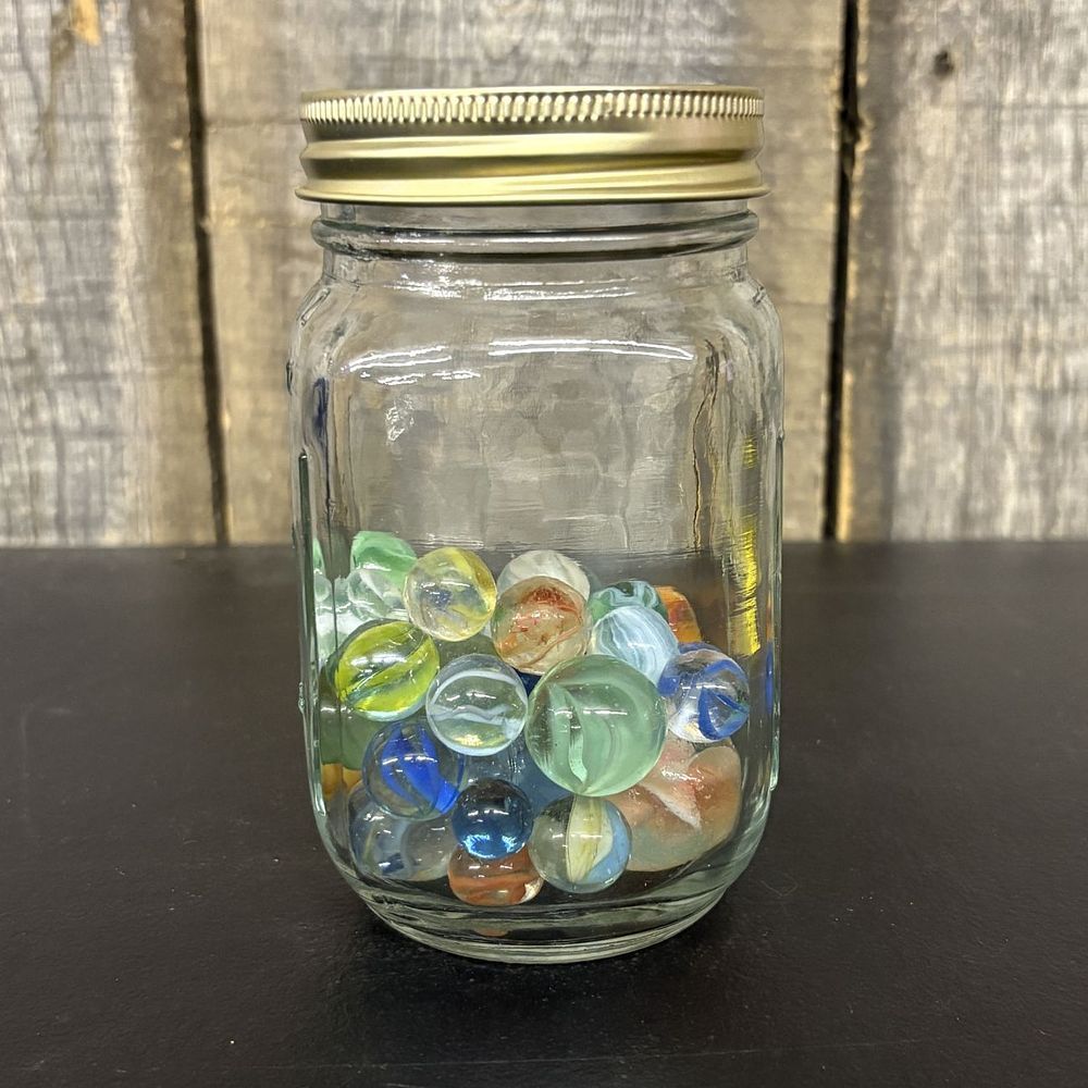 Lot 316: An Assortment of Glass Marbles Stored in a Graduated Glass Jar