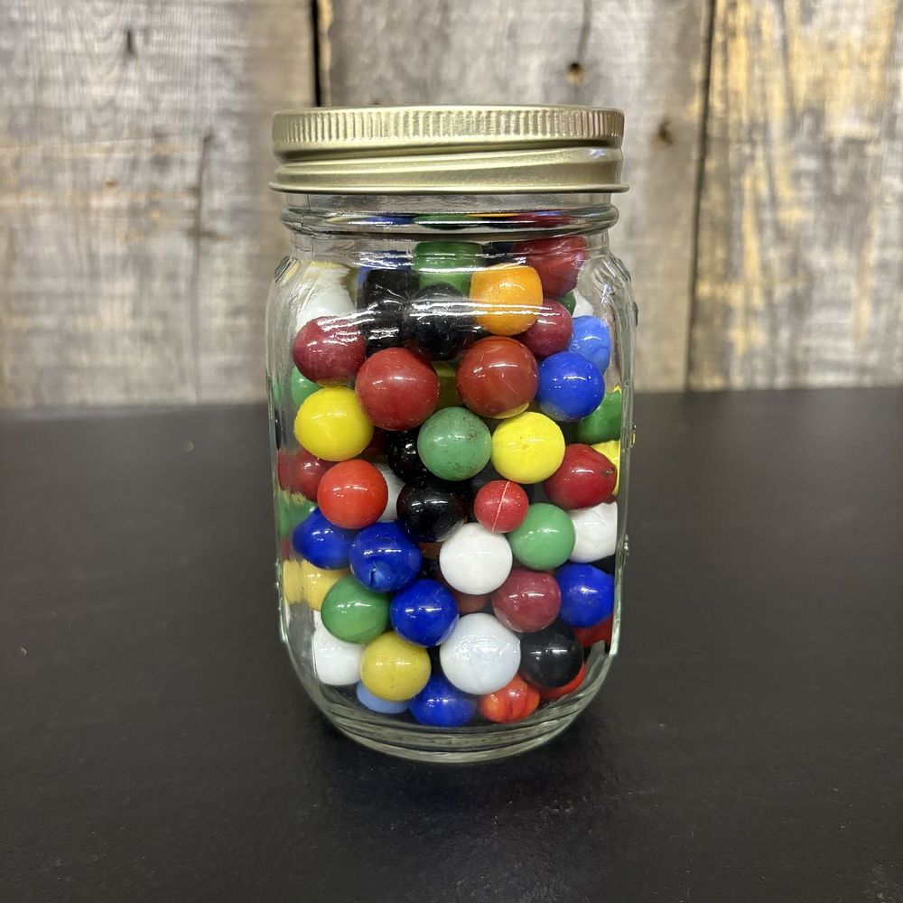 Lot 444: An Assortment of Glass Marbles in a Graduated Glass Storage Jar