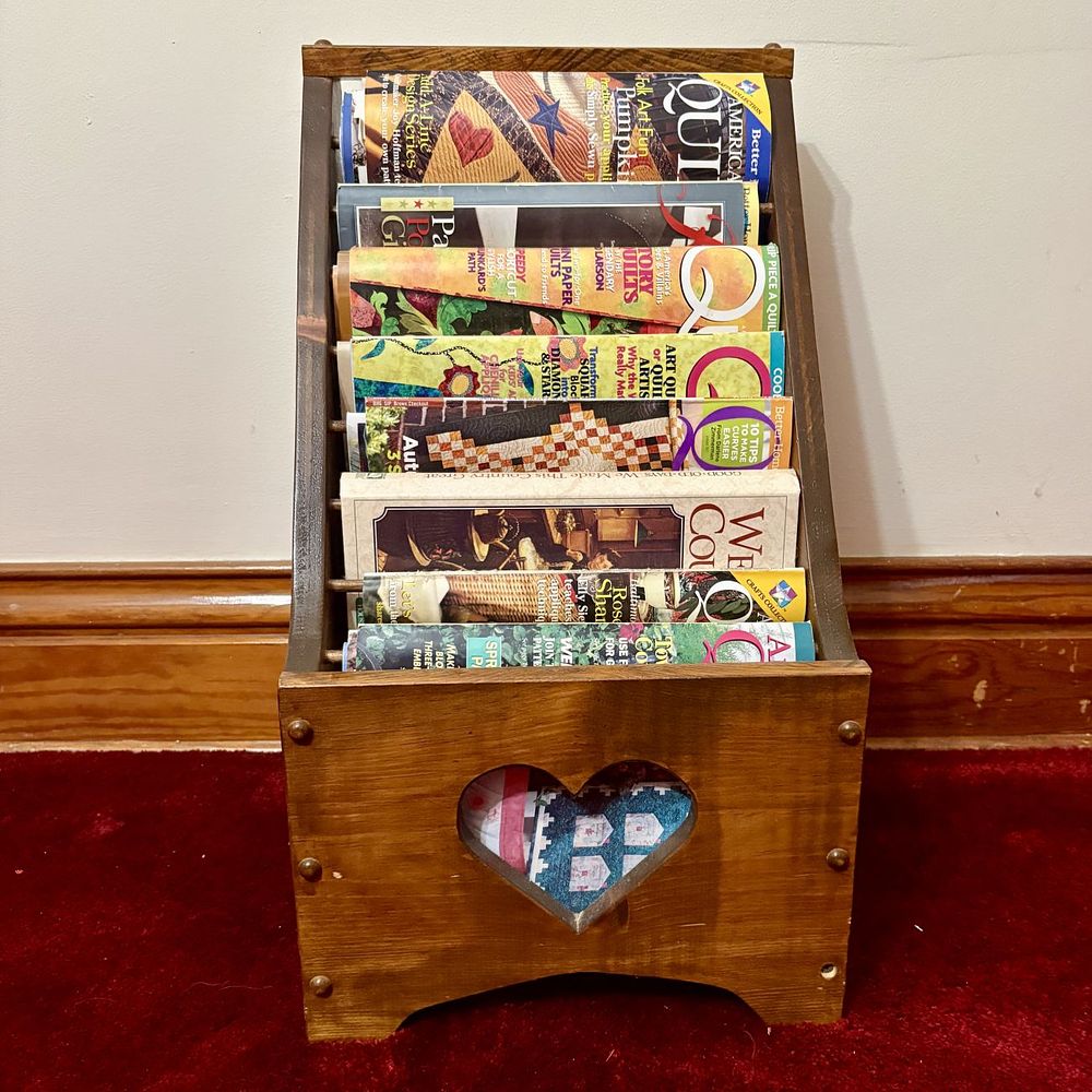 Lot 503: A Collection of Quilting Periodicals and Books in a Wooden Heart Magazine Rack