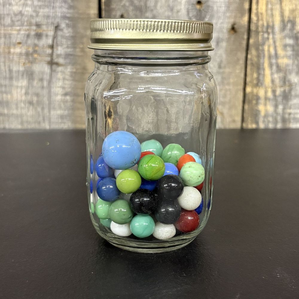 Lot 561: A Collection of Assorted Glass Marbles in a Clear Glass Jar