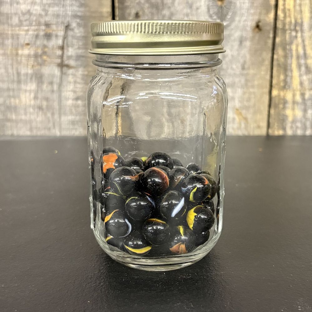 Lot 654: A Collection of Black Glass Cat Eye Marbles in a Graduated Glass Jar
