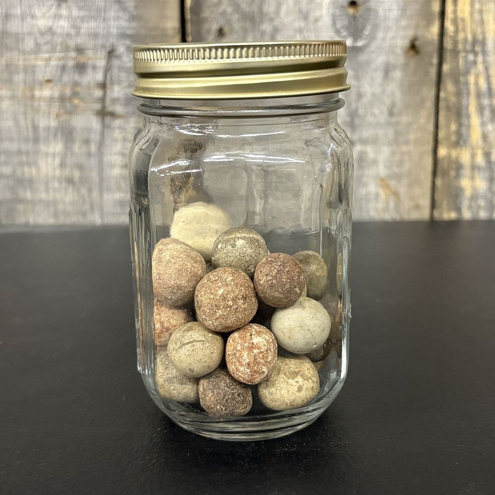 Lot 663: A Collection of Antique Clay Marbles in a Graduated Glass Jar